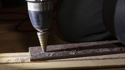 Drilling,Metal,Plate,With,Step,Drill,Bit,Using,Electric,Drill