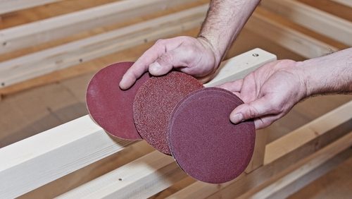 Sandpaper,Circles,In,Carpenter,Hands,Against,The,Background,Of,Wooden