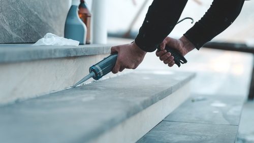 A,Person,Is,Carefully,Applying,A,Bead,Of,Sealant,Along